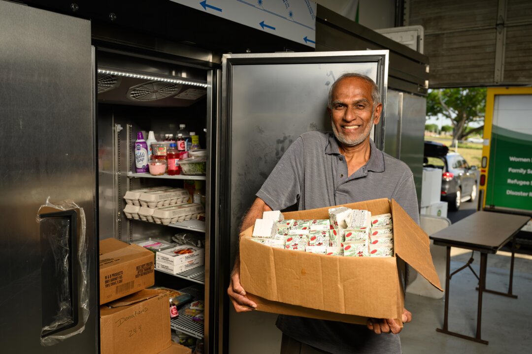 Man smiling, holding box of donated food